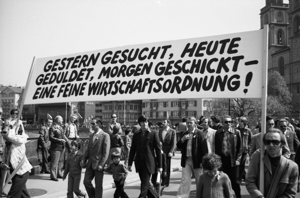 “Ricercati ieri, tollerati oggi, cacciati domani –che sistema economico distinto!”. Corteo del primo maggio, Münsterbrücke Zurigo, 1976. Fonte: Archivio sociale svizzero, Sozarch_F_5069-Na-003-018.
